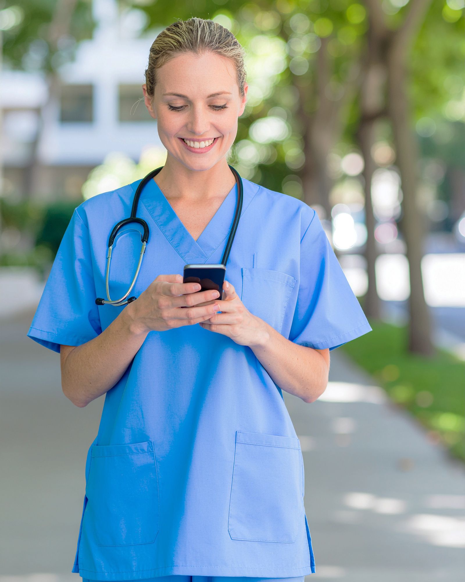 Eine Pflegerin tippt auf ihrem Smartphone