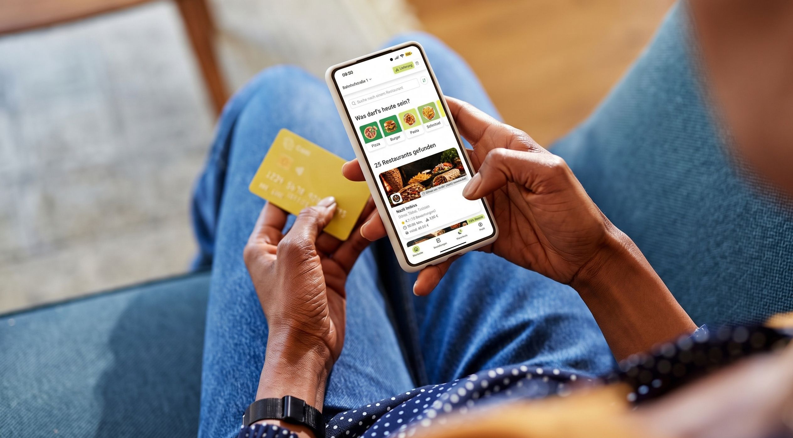 Eine Person zahlt in einer App, auf einem Sofa sitzend.